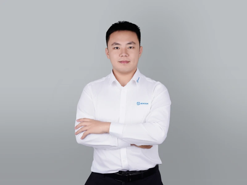 Roy, wearing a white shirt, has his arms crossed over his chest.