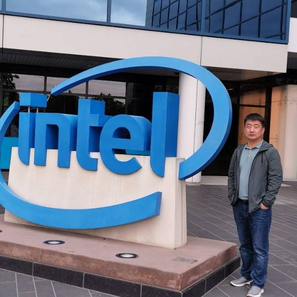 Samuel is standing in front of the Intel company gate.