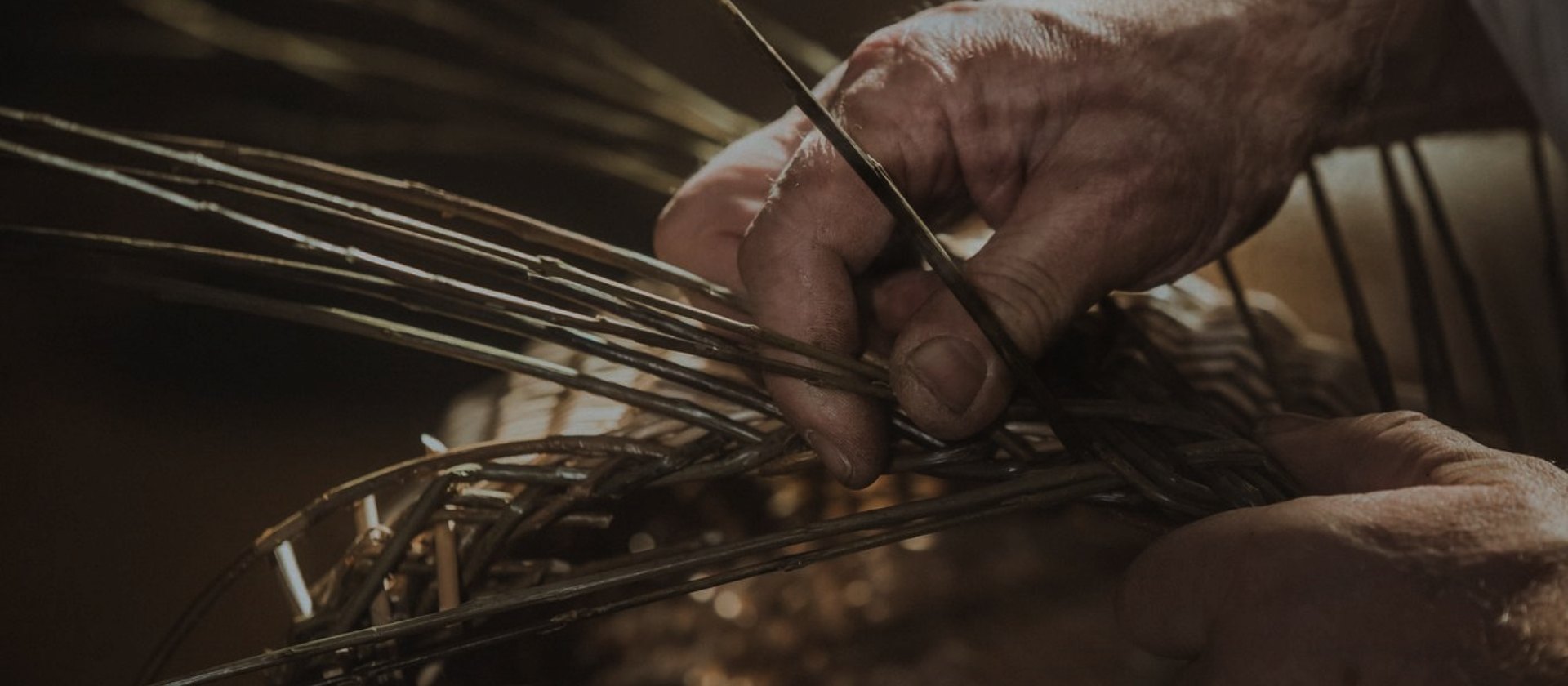 Un vieil homme est le tissage d'un panier avec des osier.